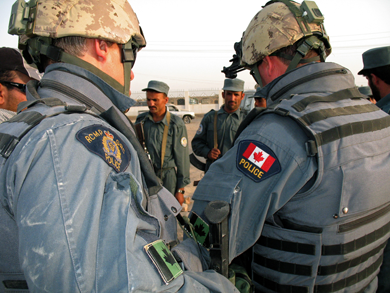 Des membres de la Gendarmerie royale du Canada servant à l’emplacement de l’Équipe de reconstruction  des Forces canadiennes, à Kandahar, en Afghanistan, avec des membres du 1er Peloton de police militaire